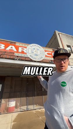 Personne devant un restaurant barbecue avec enseigne indiquant Louie Mueller, spécialité viande barbecue texan.