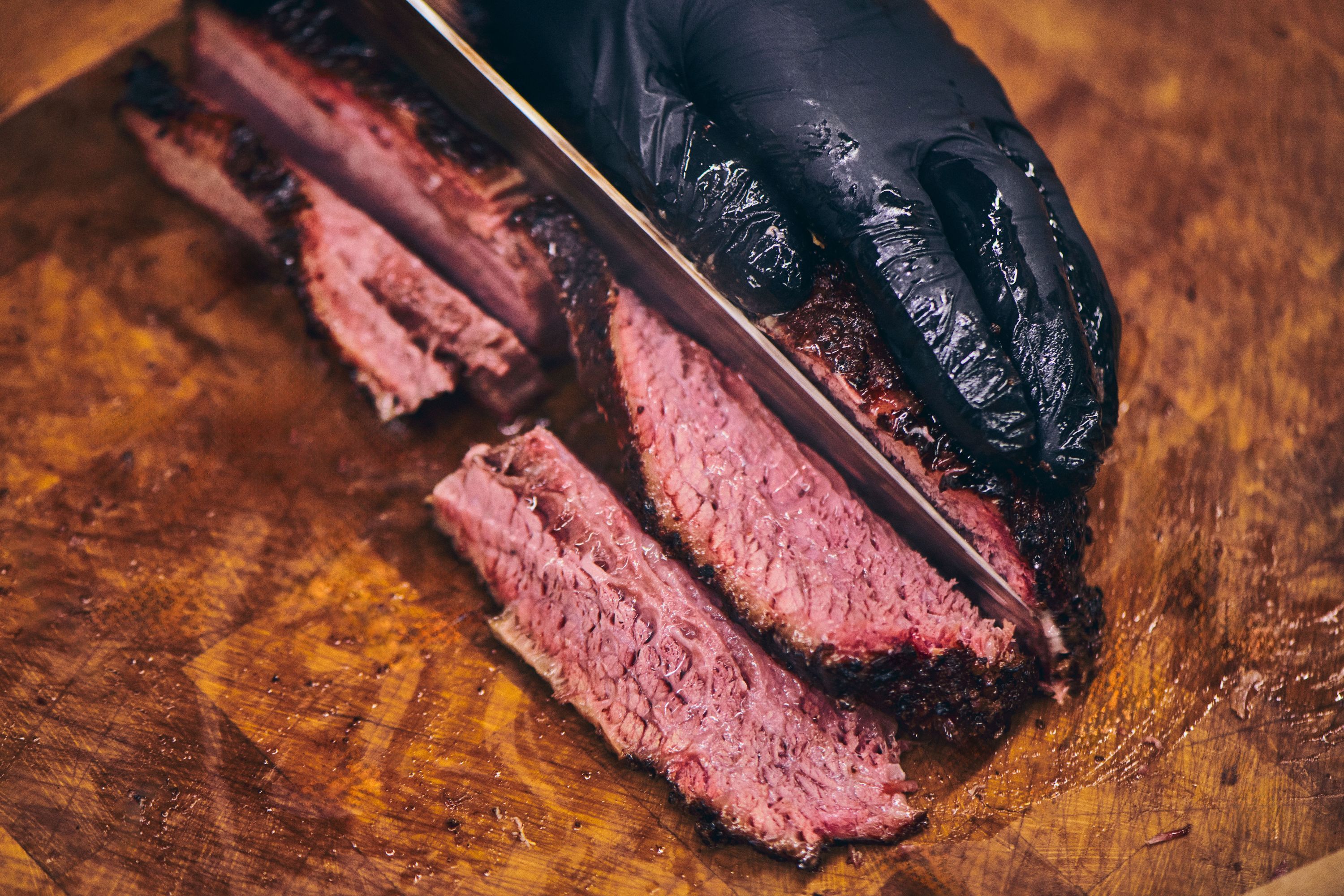Tender brisket being sliced on a wooden cutting board, showcasing its juicy interior.