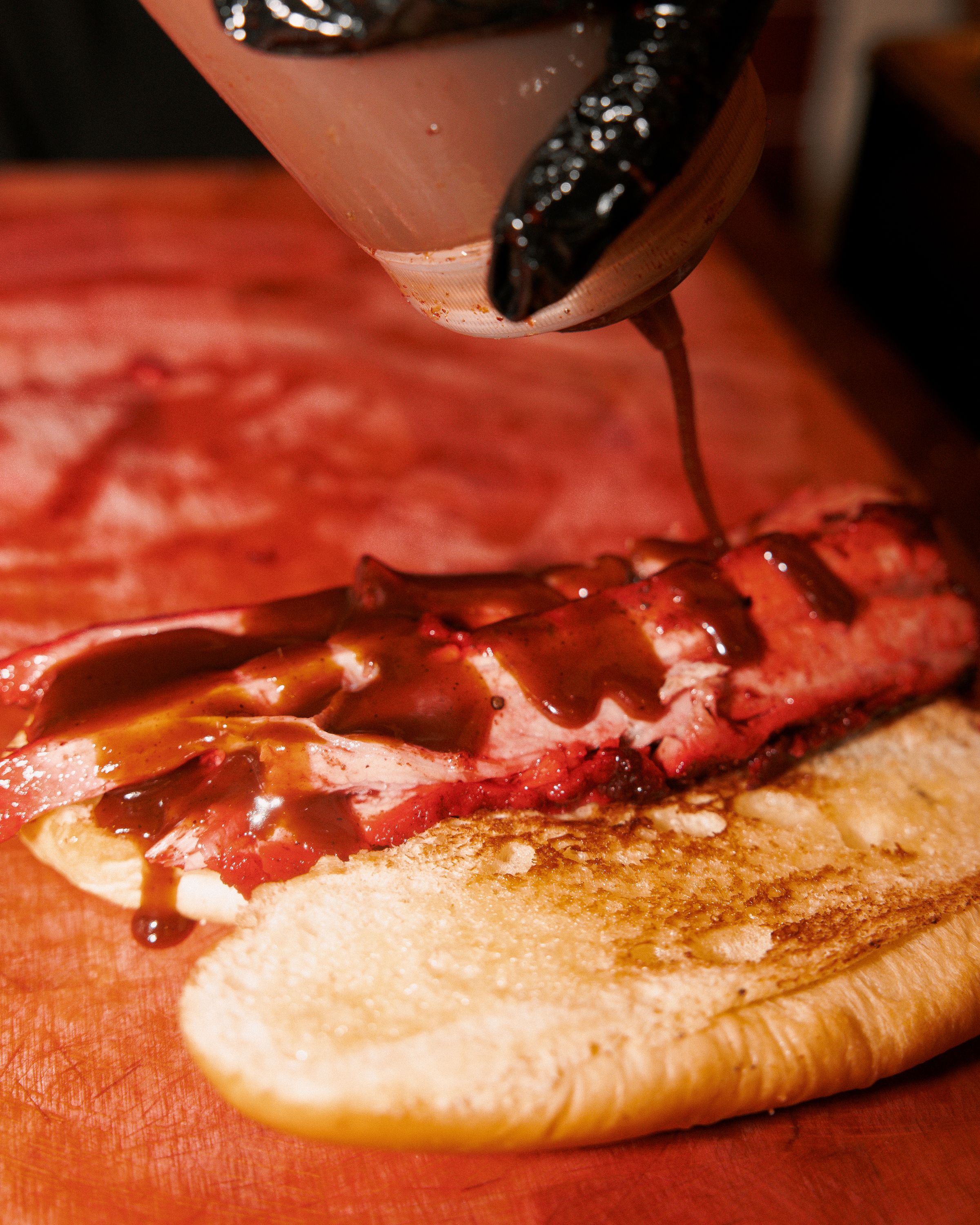 Brisket généreusement nappé de sauce barbecue sur un pain grillé au MELT DELI, un restaurant de viande à Paris.