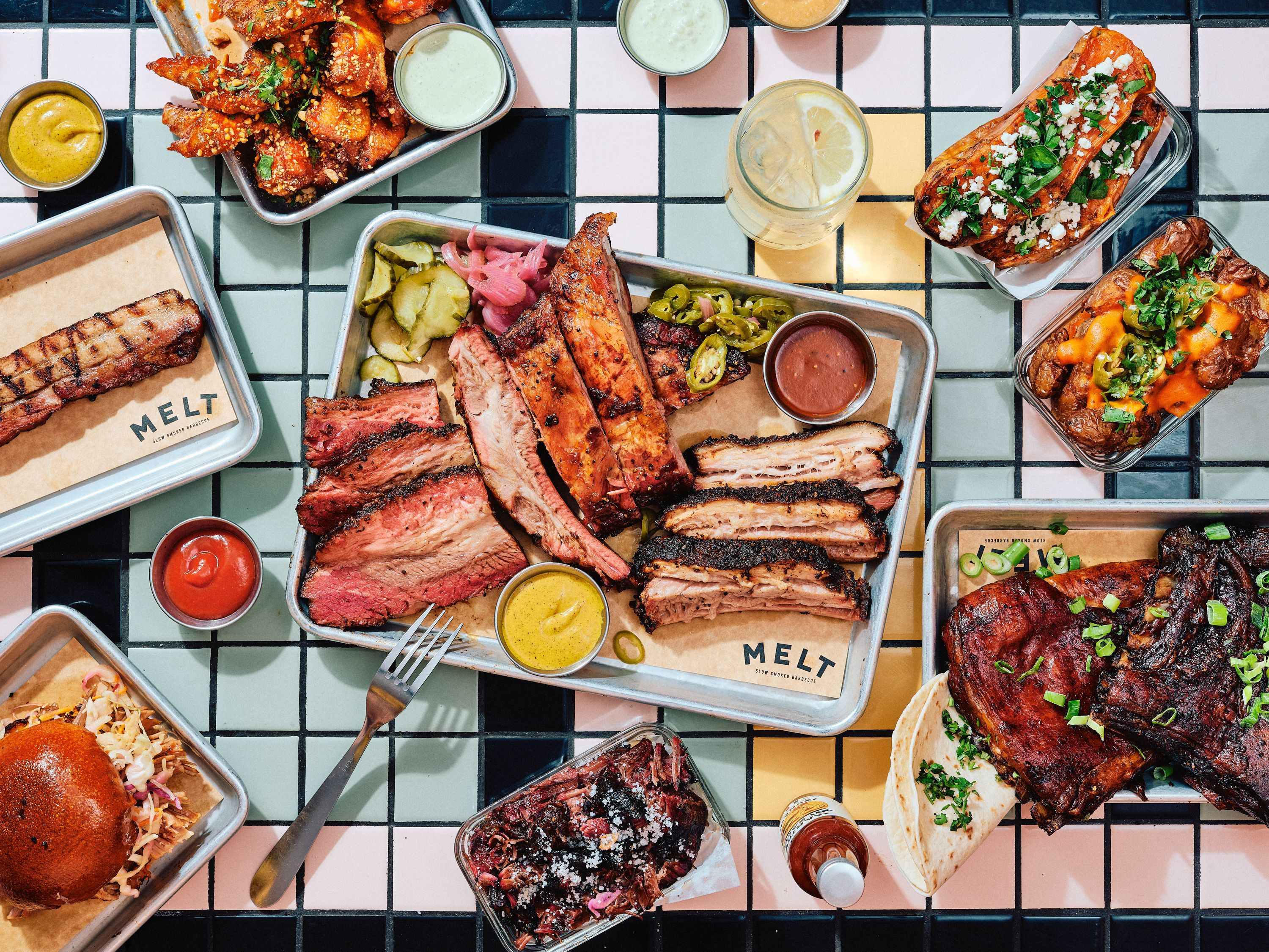 Assortiment de viandes barbecue texan, incluant brisket et pulled pork, servi avec des accompagnements.