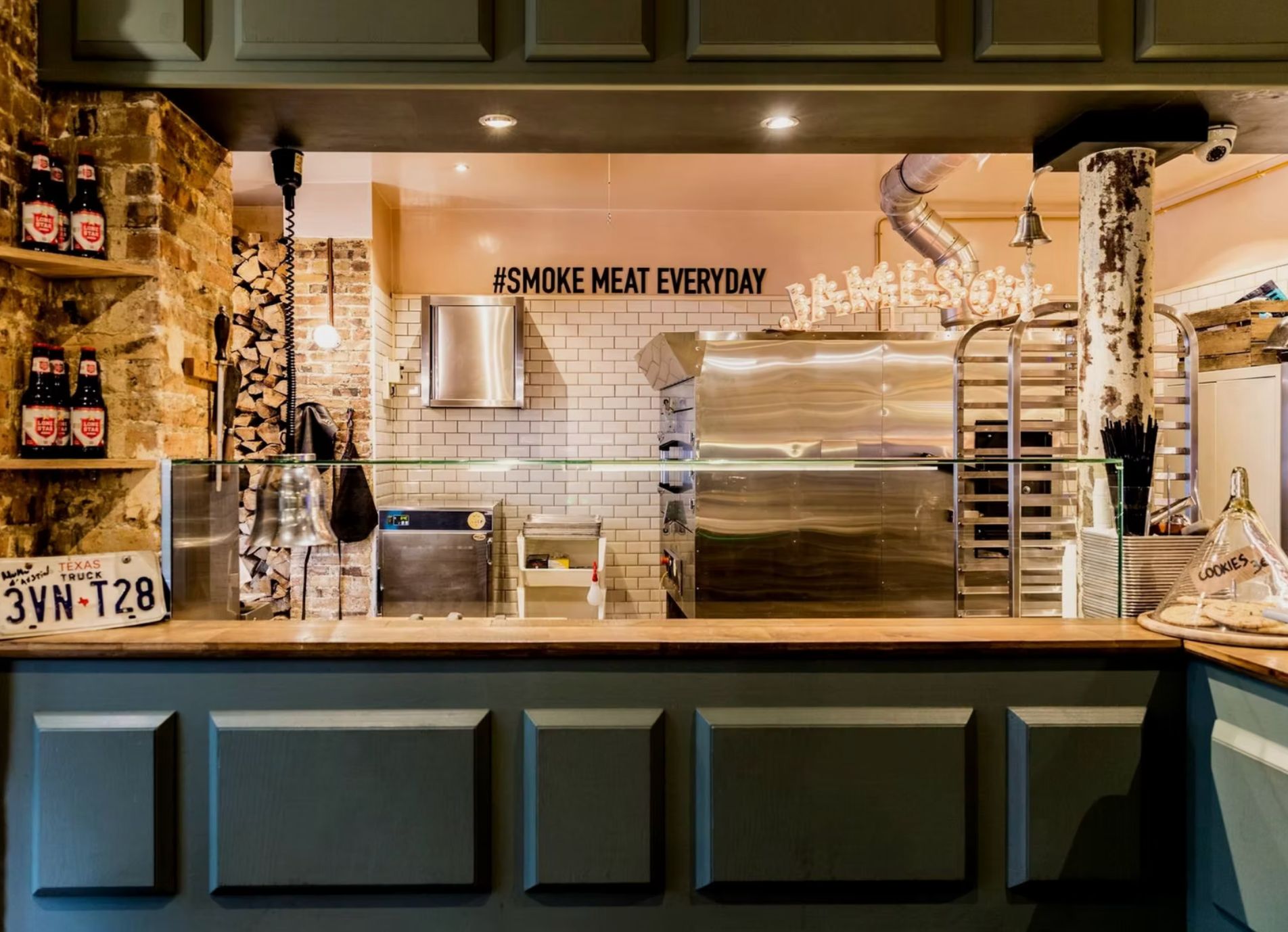 Interior view of Melt Oberkampf showcasing the kitchen and a bar area, emphasizing its barbecue offerings.