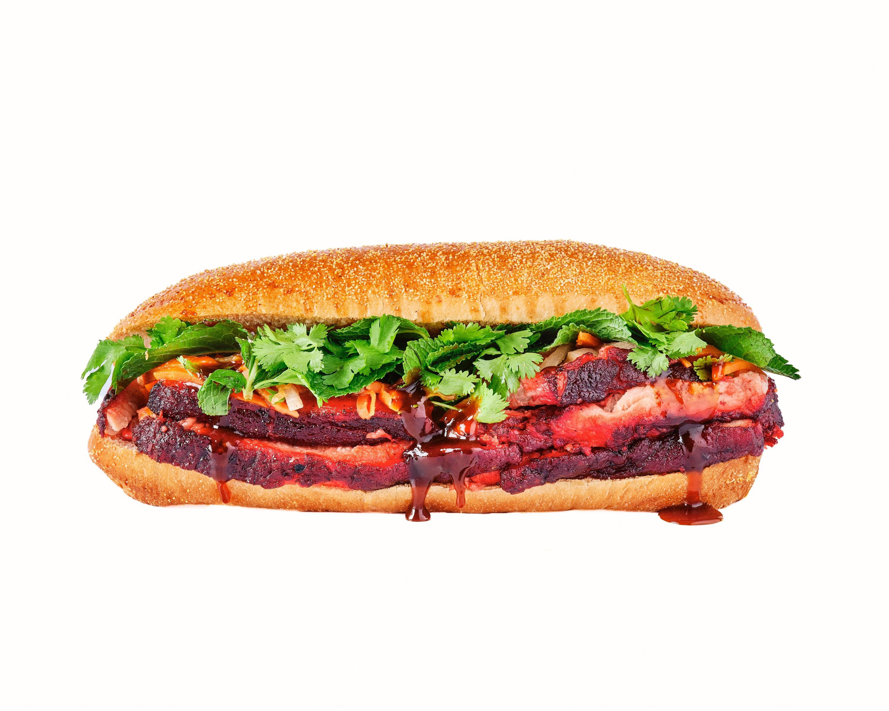 Sandwich garni de brisket, sauce barbecue texan, herbes, sur pain croustillant.