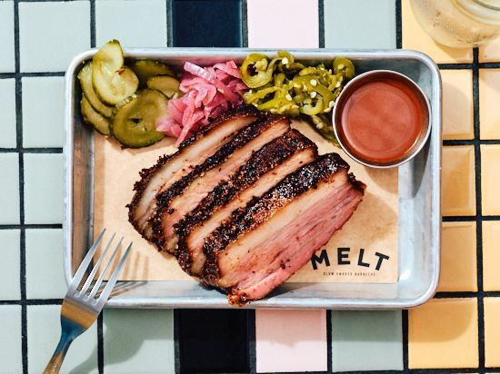 Brisket de barbecue texan accompagné de cornichons, oignons et sauce, à découvrir dans le meilleur restaurant de viande.
