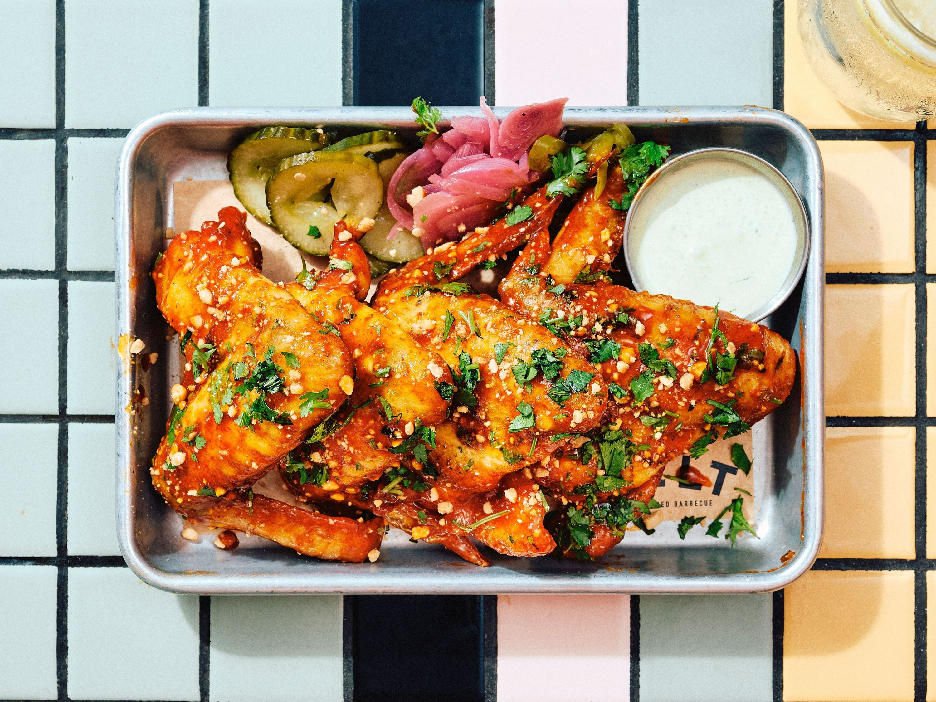 A plate of salad topped with grilled chicken, cheese shavings, croutons, and pickled onions.