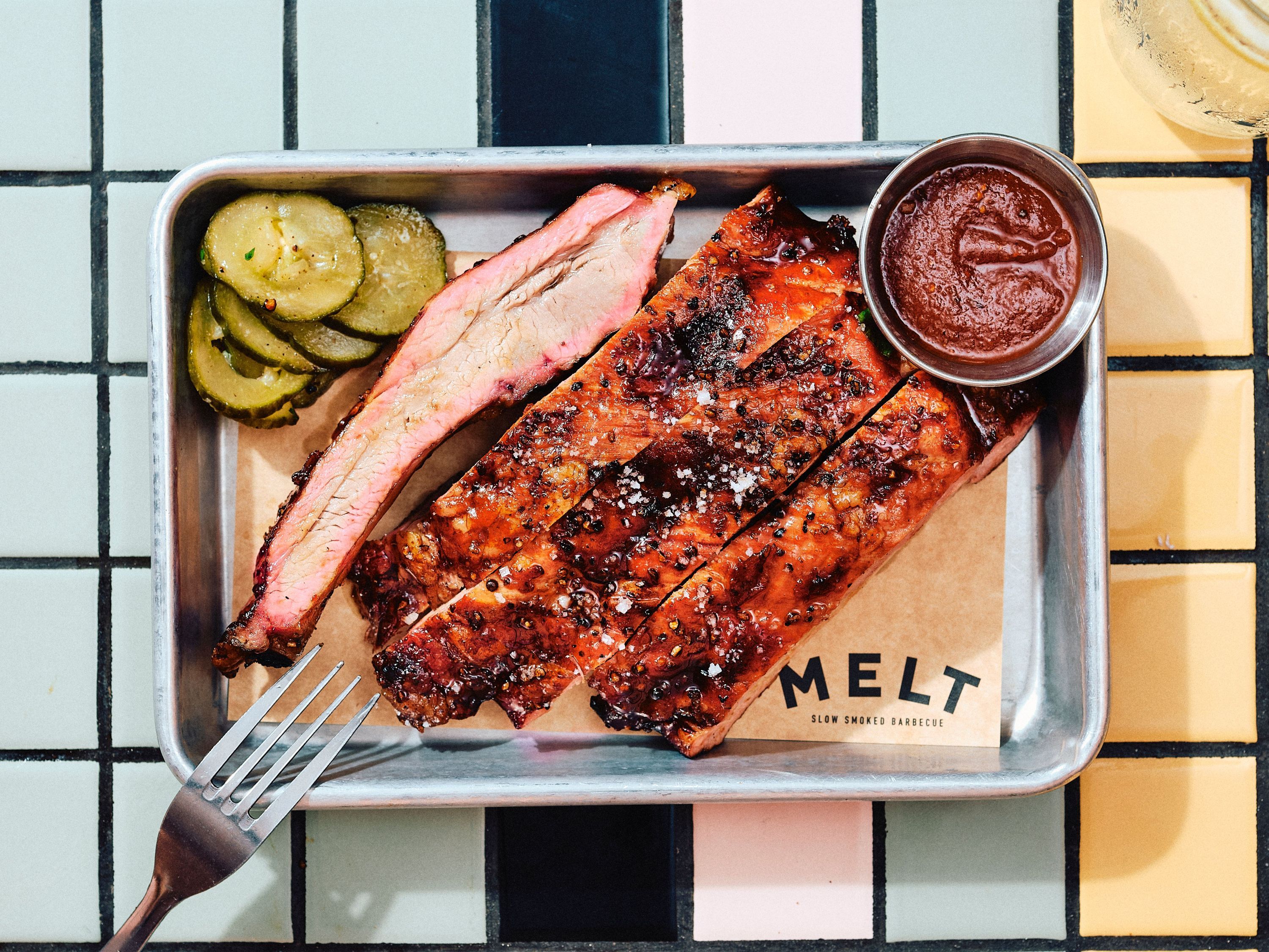 Côte de bœuf barbecue texan avec tranches de cornichon et sauce à côté, servie au MELT BATIGNOLLES.