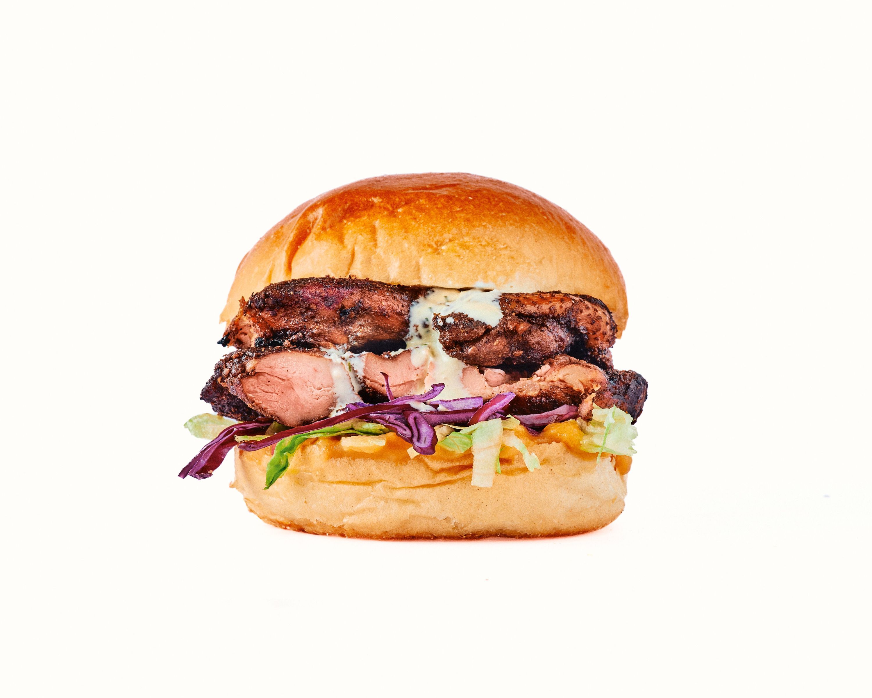 A pulled pork sandwich topped with slaw and barbecue sauce, served on a soft bun.