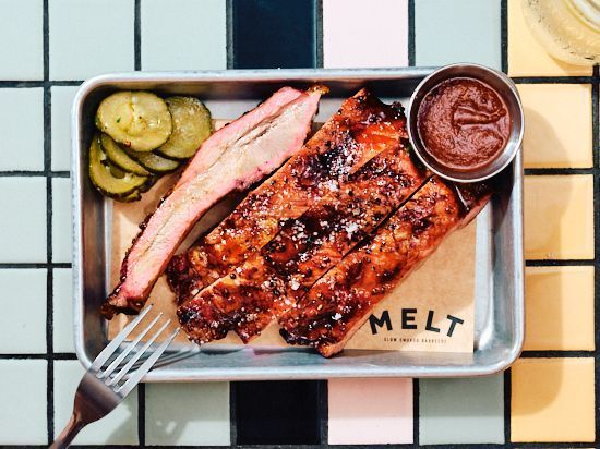 Échantillon de côtes barbecue texan servi avec des cornichons et de la sauce dans un restaurant de viande à Paris.