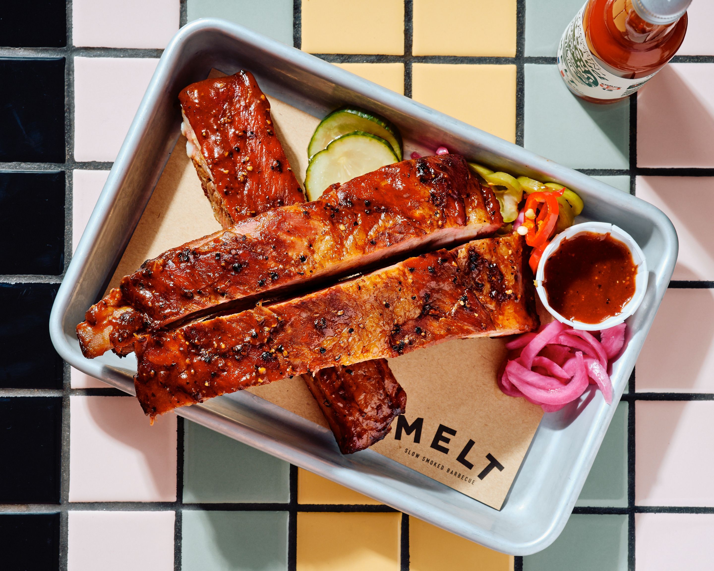 Côtes de porc barbecue, accompagnées de sauce, de légumes frais et d'un quartier de citron.