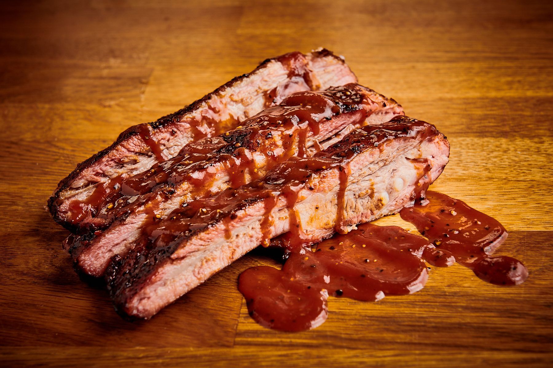 Brisket texan nappé de sauce barbecue, présenté sur une surface en bois.