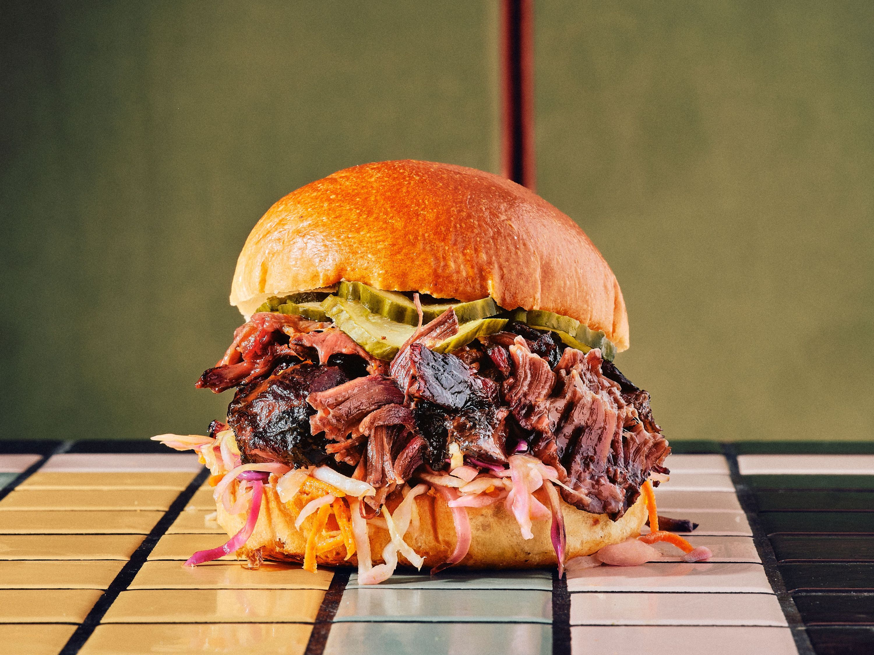 Savoureux sandwich au brisket, garni de chou et de cornichons, sur pain moelleux.
