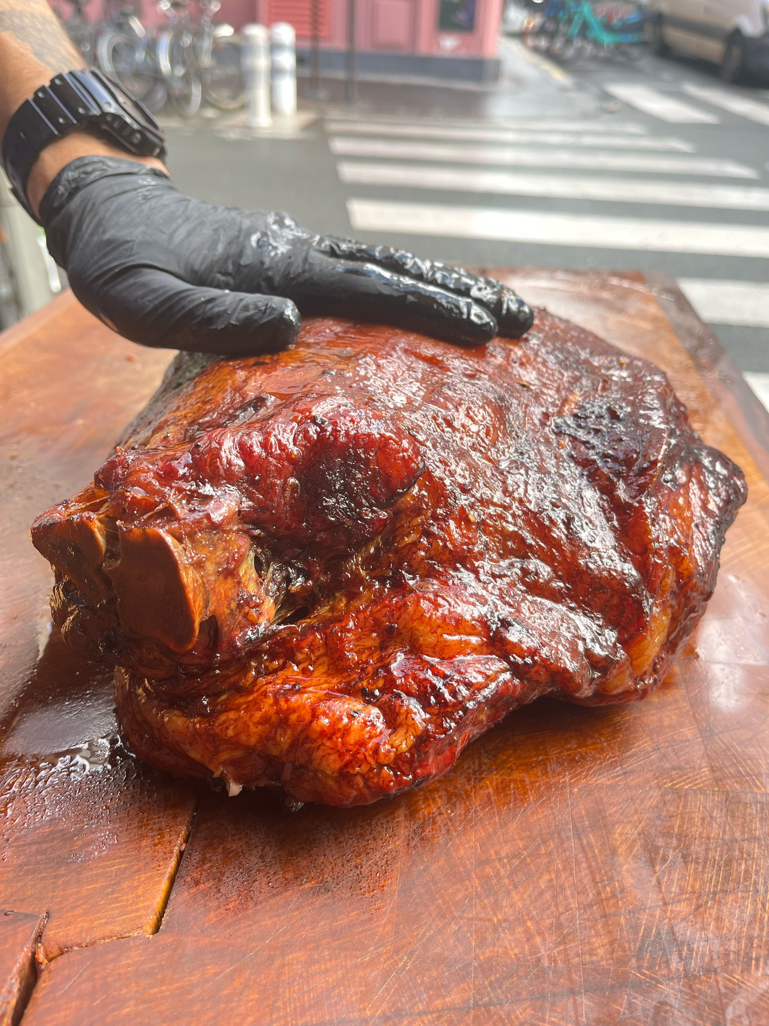 A large, glazed brisket on a wooden cutting board, showcasing its rich color and texture, prepared for serving.