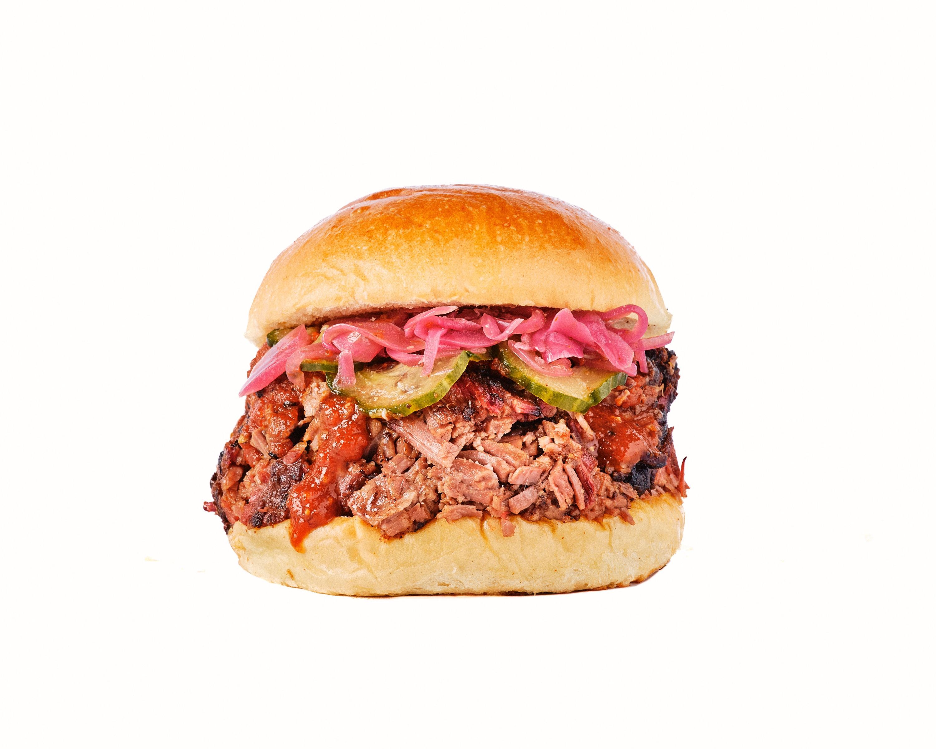 Burger avec brisket, garnitures de pickles et d'oignons marinés, pain brioché.